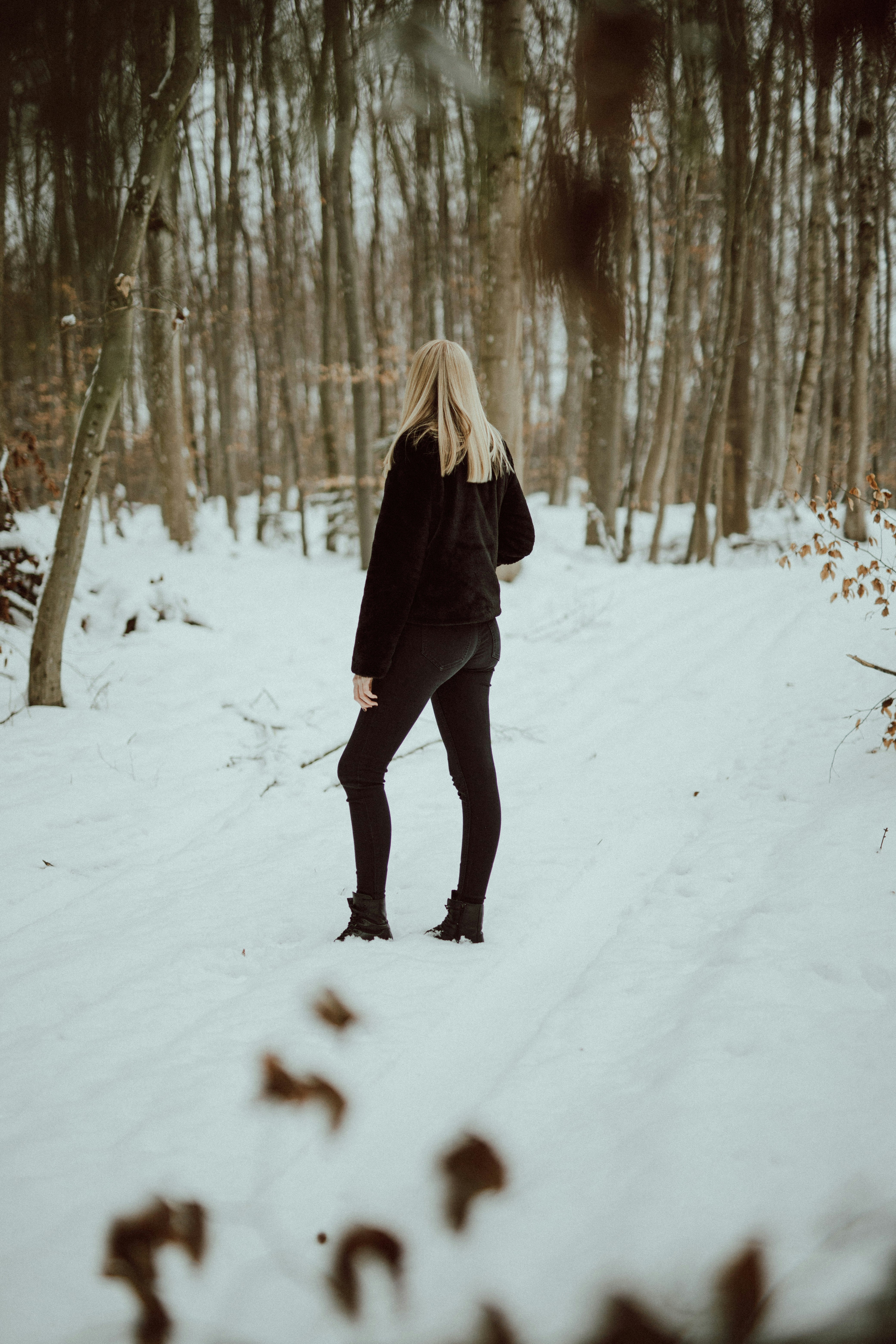 woman in black jacket and black pants walking on snow covered ground during daytime
